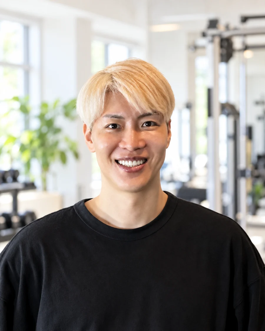 HABIT. bloom 代表トレーナーの中義範。スタジオのトレーニング機器を背に、笑顔で正面を向いている様子。