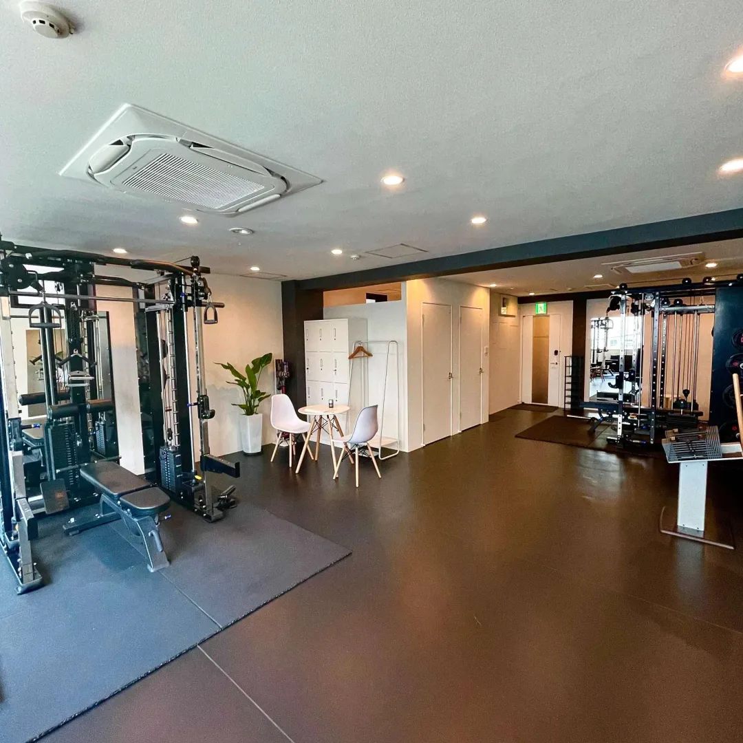 HABIT. bloomのスタジオ内観。トレーニングマシンと、振り返りに使うテーブル席、更衣スペースのある清潔な空間